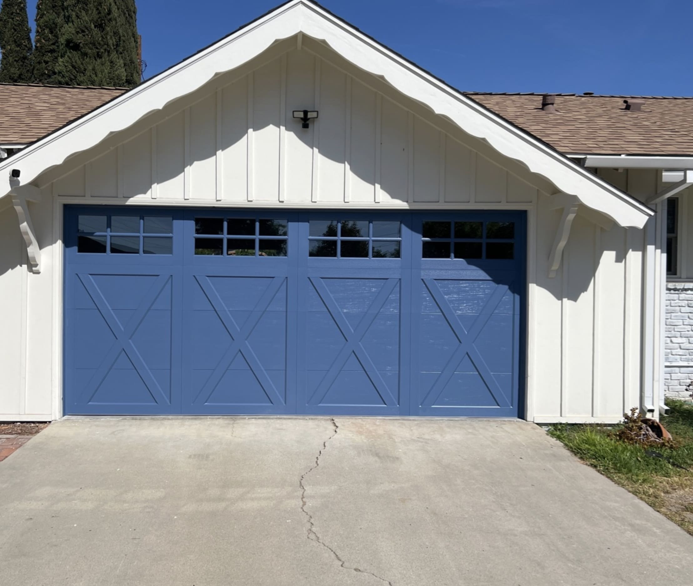 Blue carriage-style garage door on a white home, showcasing a clean and well-maintained exterior.